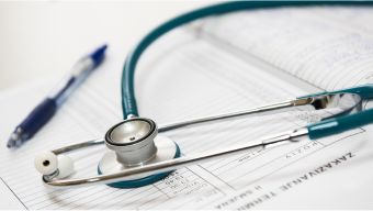Stethoskop auf Abrechnungsformular mit Kugelschreiber – Symbolbild für medizinisches Forderungsmanagement / Stethoscope and pen on a billing form, symbolizing medical receivables management