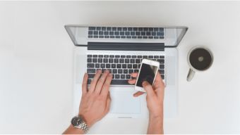Person arbeitet an Laptop und Smartphone – Symbolbild für digitale Kommunikation im Forderungsmanagement / Person working on a laptop and smartphone, symbolizing digital communication in receivables management