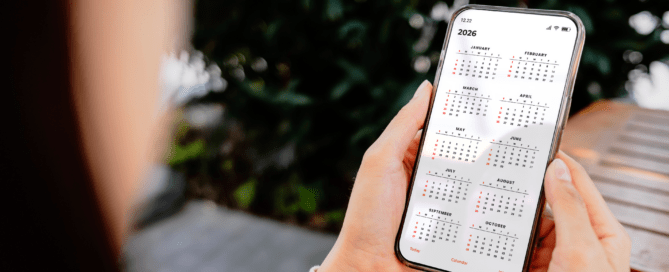Frau hält ein Smartphone mit geöffnetem Jahreskalender 2026 in der Hand, Monate Januar bis Oktober sichtbar.