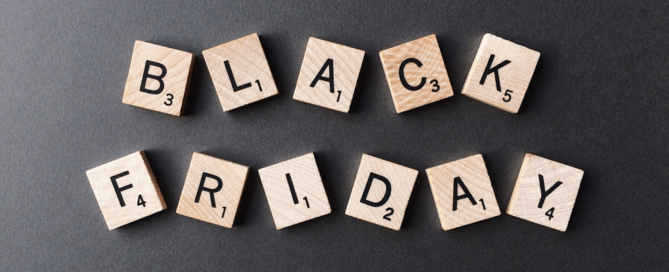 Der Schriftzug 'Black Friday' aus hellen Holz-Scrabble-Steinen auf dunkelgrauem Hintergrund.